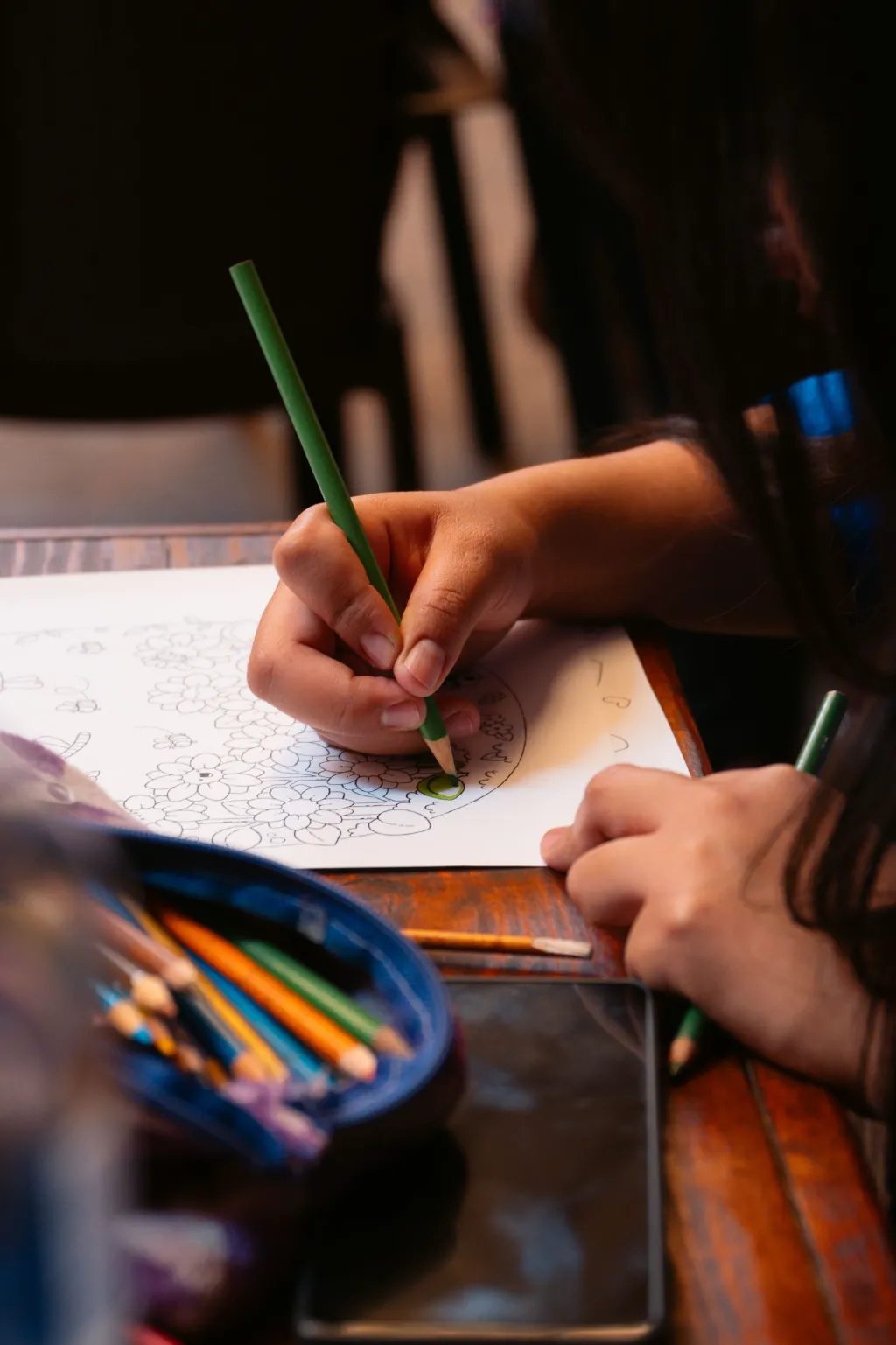 Gros plan sur une main d’enfant qui dessine avec un crayon de couleur