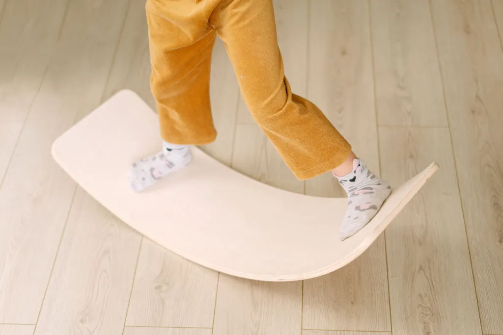Les pieds d’un enfant en chaussettes sur une planche d’équilibre en bois