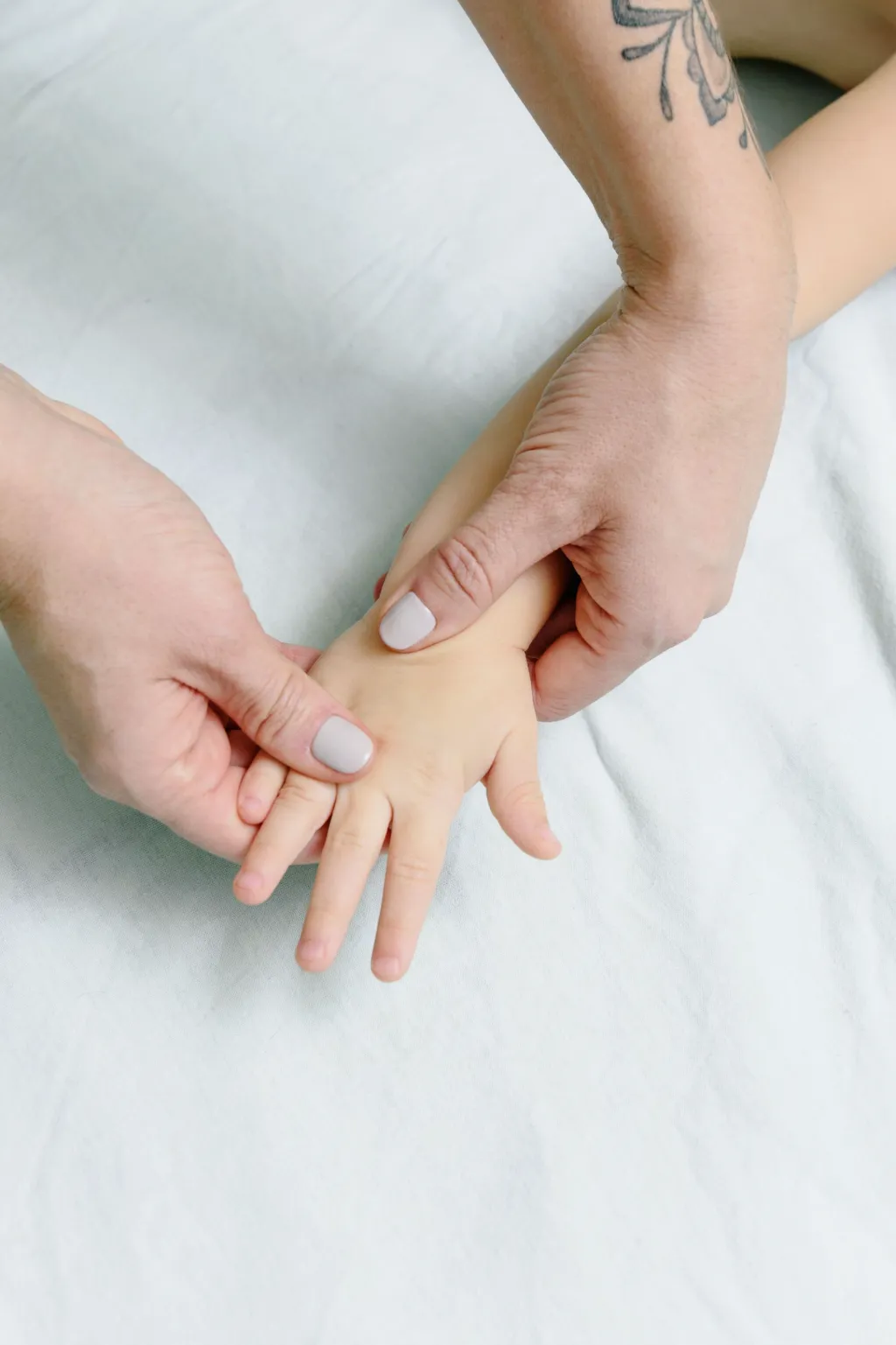 Des mains d’adulte massent doucement la main d’un enfant
